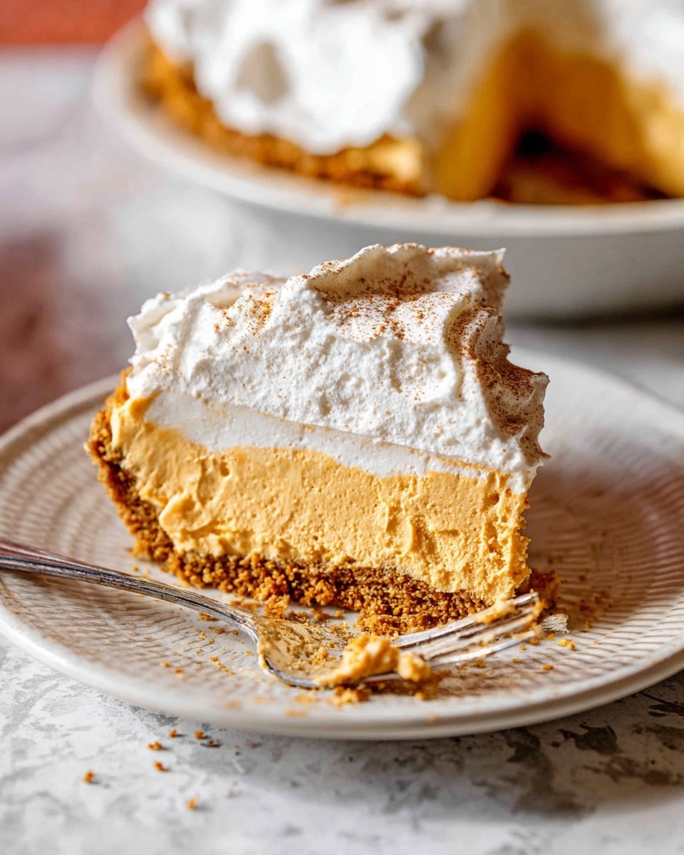 A slice of pie with three distinct layers sits on a white plate with a textured edge. The bottom layer is a crumbly, golden-brown crust. Above the crust is a thick, smooth, light orange filling layer. The top layer is fluffy white whipped cream, slightly uneven with a light dusting of cinnamon or spice powder. Next to the slice is a silver fork with some whipped cream and filling residue on it. The background shows a matching pie dish with more pie and a white marbled texture surface underneath. photo taken with an iphone --ar 4:5 --v 7