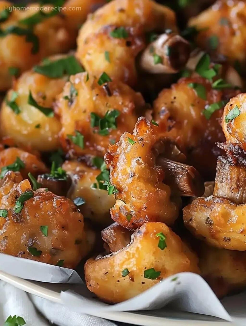 A close-up of golden brown fried cauliflower pieces with a crispy texture, each piece showing a rough, bubbly surface with darker browned spots. The cauliflower is scattered with small, fresh green parsley flakes, adding a touch of color. Among the cauliflower, there are visible brown roasted mushroom stems with a slightly shiny and soft texture. All the pieces rest on white parchment paper, inside a white dish, set on a white marbled surface. photo taken with an iphone --ar 4:5 --v 7