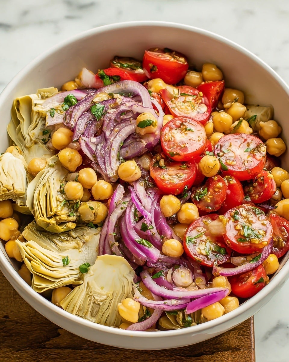 A white bowl filled with a colorful salad is set on a white marbled texture. The salad has three main layers: The bottom layer is yellow chickpeas giving a soft texture. The middle layer shows sliced bright red cherry tomatoes and white artichoke hearts with light green edges, both rough and juicy. On top, there are thin purple rings of red onions and small pieces of green herbs scattered all over to add freshness. The ingredients mix creates a fresh and vibrant look with contrasting colors and textures. photo taken with an iphone --ar 4:5 --v 7