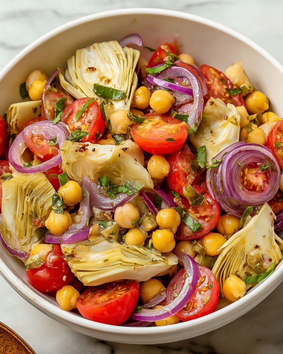 A white bowl filled with a fresh salad showing multiple layers: the bottom layer has pale yellow chickpeas, topped with bright yellow artichoke halves positioned upright, thin curved slices of purple-red onion scattered evenly, and small, round, red cherry tomato halves placed throughout. Bright green chopped herbs and capers are sprinkled lightly on top, adding texture and color contrast, all sitting on a white marbled surface. photo taken with an iphone --ar 4:5 --v 7