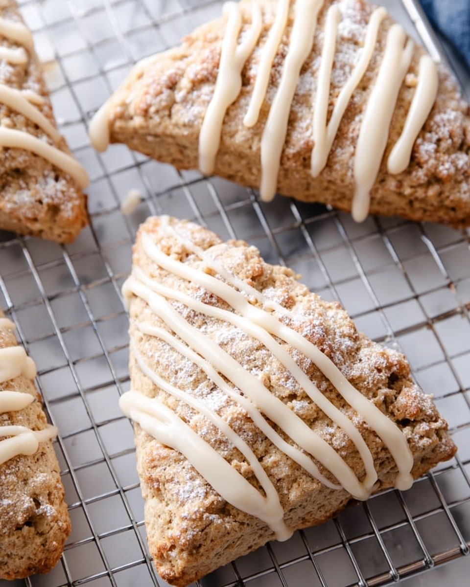 The image shows three triangular scones with a rough, crumbly texture, golden brown in color with a dusting of powdered sugar on top. Each scone is decorated with thick, creamy, off-white icing drizzled in parallel diagonal lines across the surface, with the icing slightly pooling at the edges. The scones rest on a metal wire cooling rack, and beneath the rack is a white marbled texture. The photo taken with an iphone --ar 4:5 --v 7