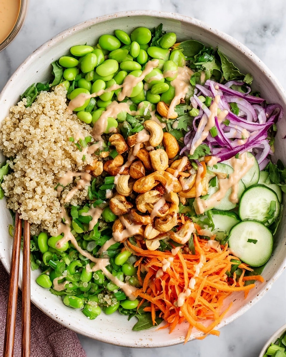 A white bowl filled with a layered salad, starting from the bottom with a bed of green leafy vegetables. Around the edges are sections of pale beige quinoa on the left, bright green edamame at the top, fresh green herbs to the right of the edamame, and thin cucumber slices to the right. There are thin strips of purple onion placed next to the cucumber and some more layered around the center. On the bottom right, there are shredded orange carrots, with chopped green snap peas next to them on the lower left side. The top center features a drizzle of creamy light tan dressing with roasted golden brown cashews scattered over it. Chopsticks rest on the edge of the bowl, sitting on a white marbled surface. Photo taken with an iphone --ar 4:5 --v 7