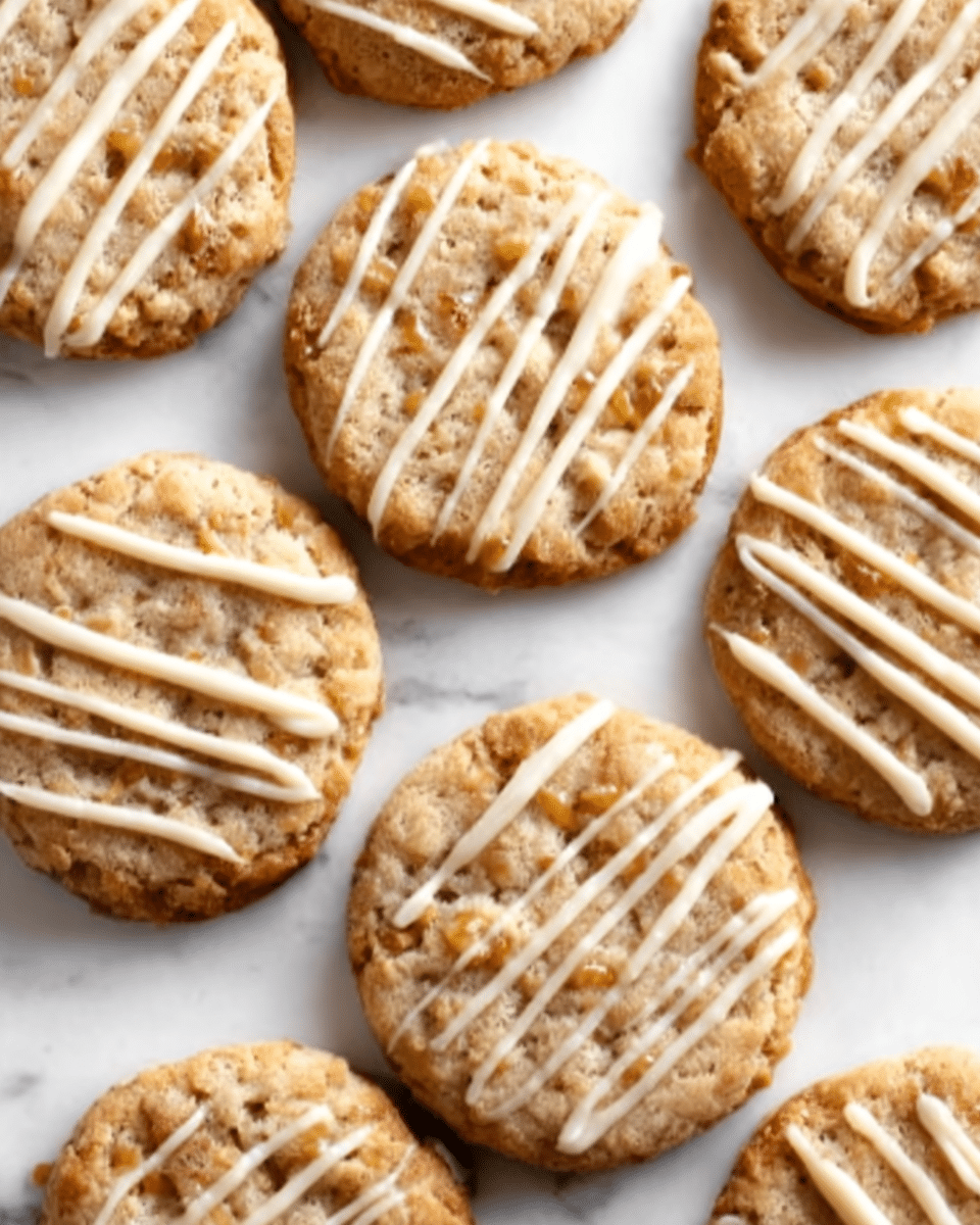 The image shows several round cookies arranged close together on a white marbled surface with a top-down view. Each cookie has a golden-brown color with a slightly rough texture, visible bits of what looks like oats or nuts throughout. On top of each cookie, there are thin, diagonal lines of creamy white icing drizzled unevenly, creating a contrast in color and texture. The cookies appear soft yet slightly crunchy around the edges, giving a homemade look. Photo taken with an iphone --ar 4:5 --v 7