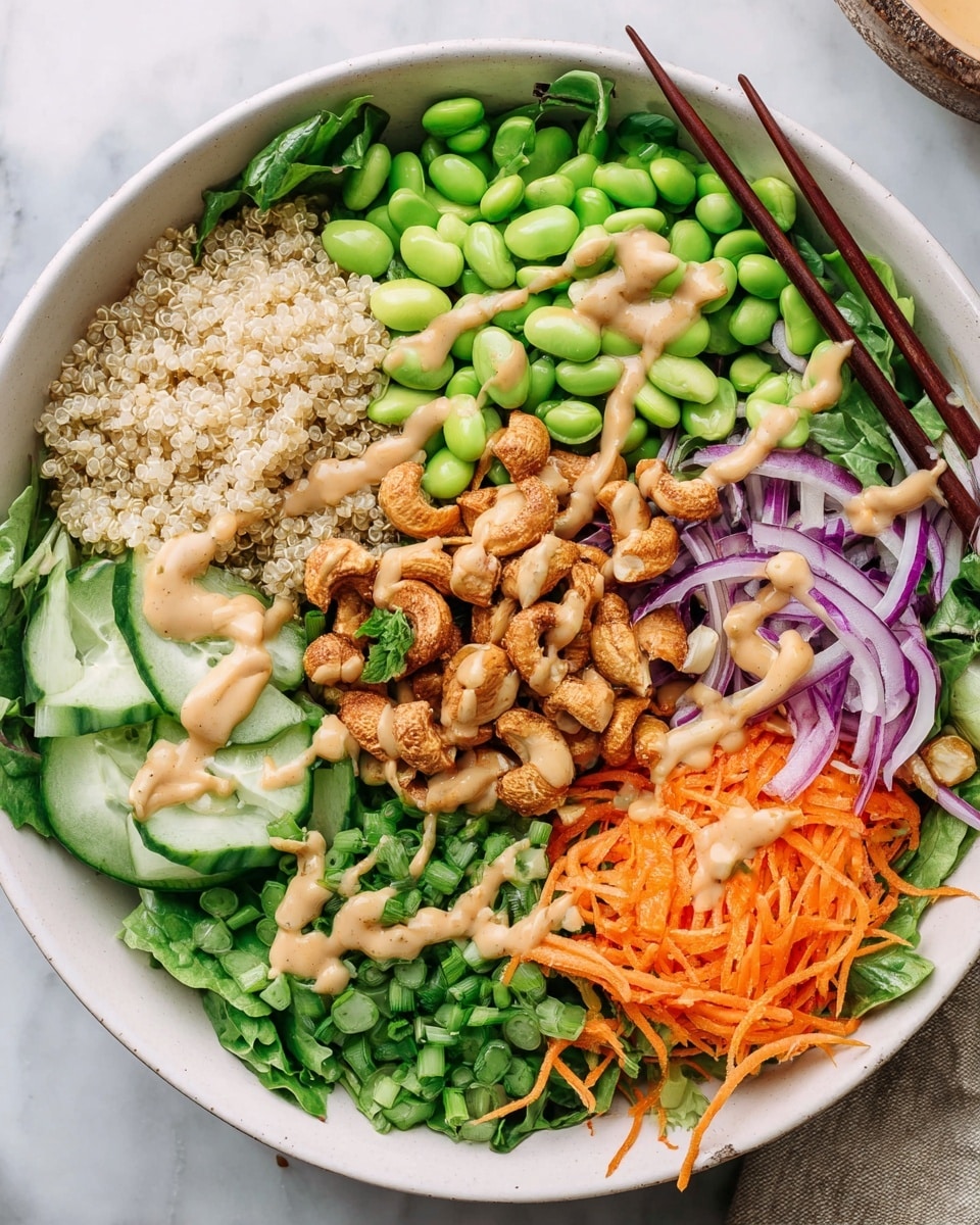 A white bowl contains a colorful layered salad with eight distinct parts. On the bottom left, there is a pile of light yellow quinoa grains next to chopped green snap peas. Above that is a cluster of edamame beans with dark green skins. Thinly sliced red onion, light purple with white veins, rests near fresh cilantro leaves. On the opposite side, cucumber slices are stacked in a neat area, and under them are shredded orange carrots mixed with more thin red onion slices. On top of the salad is a creamy beige dressing drizzled over roasted, golden brown cashews that are slightly charred. The bowl sits on a white marbled surface, with gold-colored chopsticks placed at the top left side of the bowl. Photo taken with an iphone --ar 4:5 --v 7