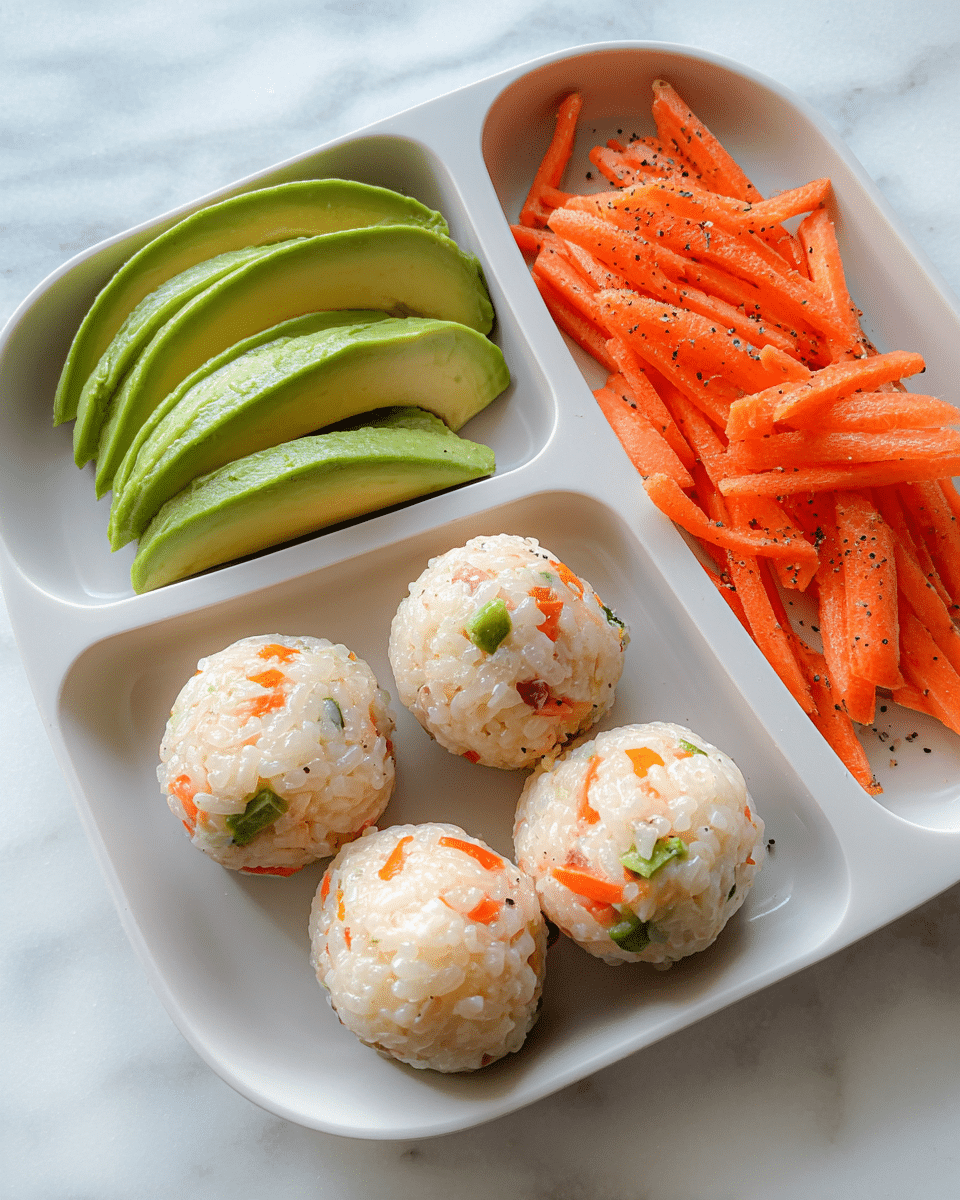 A white divided plate with three sections holds a visually appealing meal: the largest section contains six round rice balls speckled with small pieces of green bell pepper, orange carrot, and light onion, each ball smooth and compact; the top left section holds multiple slices of fresh avocado, layered neatly in parallel, showing vibrant green and light yellow tones with a soft texture; the top right section is filled with thin strips of bright orange carrots that look fresh and slightly wet, seasoned lightly with black pepper; the whole plate sits on a white marbled surface. photo taken with an iphone --ar 4:5 --v 7