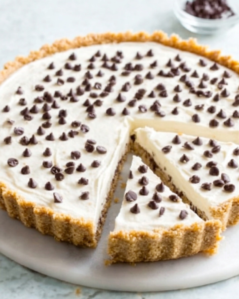 The image shows a close-up of a round pie with one slice cut out, placed on a white marbled surface. The pie has three visible layers: a golden brown crust at the bottom with a crumbly texture, a middle layer of smooth, creamy white filling, and a top layer covered evenly with small, dark chocolate chips scattered all over. The edges of the crust are slightly crimped and the pie looks fresh and inviting. Photo taken with an iphone --ar 4:5 --v 7