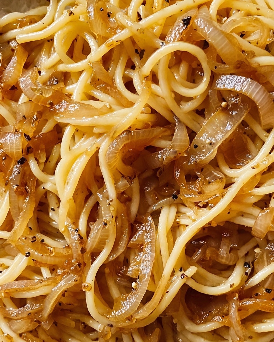 A close-up view of cooked spaghetti mixed with caramelized onions and black pepper. The pasta strands are light yellow with a glossy texture, intertwined with soft, browned onion slices that have a slightly translucent and shiny look. Small black pepper flakes are scattered throughout the dish, adding specks of dark color against the warm tones of the noodles and onions. The background features a white marbled texture, highlighting the rich colors of the food. photo taken with an iphone --ar 4:5 --v 7