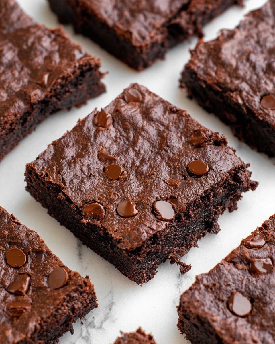 The image shows several thick, square chocolate brownies placed closely on a white marbled surface. Each brownie has a dark brown top layer with a slightly shiny texture and visible chocolate chips embedded on the surface. The middle layer appears dense and moist, with a rich, fudgy texture that looks soft and chewy. The bottom layer is similarly dark and thick, providing a solid base for the brownies. Some edges are rough while others are straight-cut, highlighting the homemade look. photo taken with an iphone --ar 4:5 --v 7